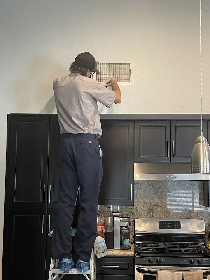 Technician inspecting an air vent during HVAC service in Jonesboro